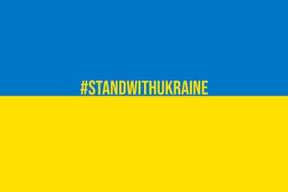 Niebiesko-żółta flaga Ukrainy, pośrodku napis #STANDWITHUKRAINE